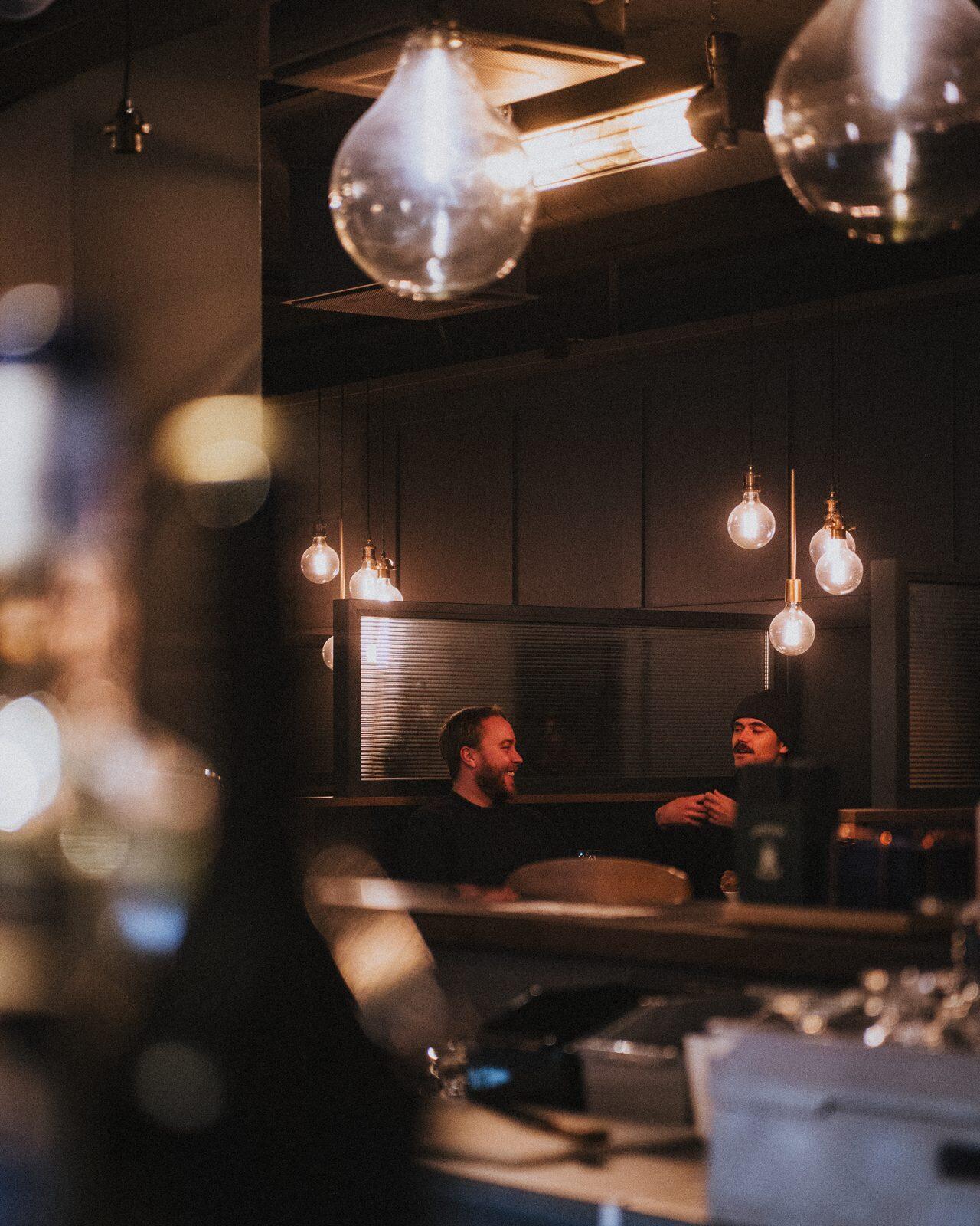 Gäster vid ett avskilt restaurangbord under hängande lampor på Olivedal.